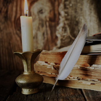 A feather pen, books and a candle.
