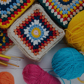 Crocheted squares with blue, red and orange fibers.